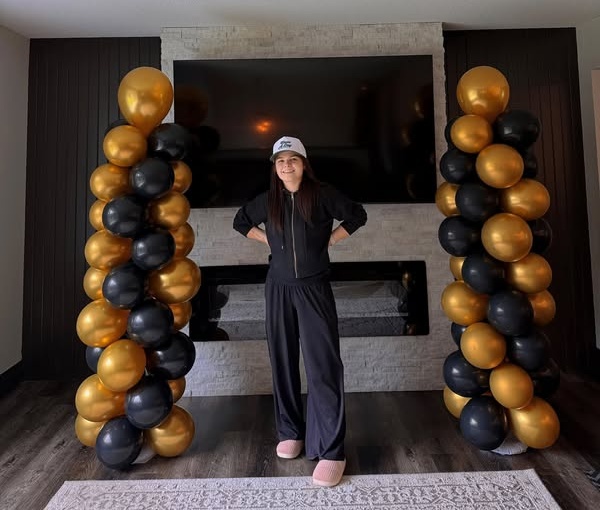 Black and gold graduation balloon towers with a person standing between them